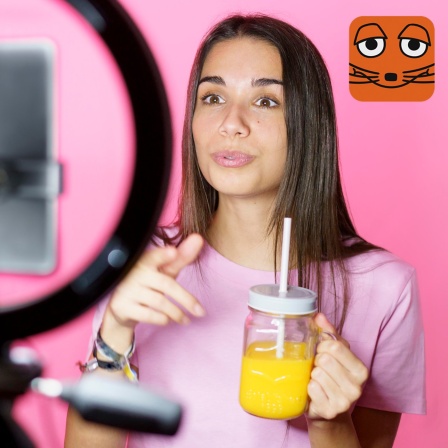 Influencerin präsentiert vor der Kamera einen Fruchtsaft