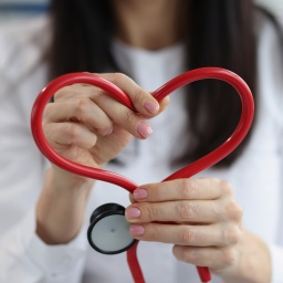 Eine Ärztin hält ein Stethoskop in Herzform hoch
