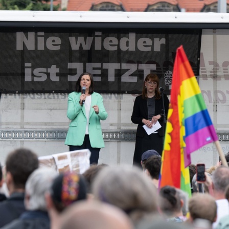 Katrin-Göring-Eckardt und Katja Meier (beide Bündnis90/Die Grünen), auf der Bühne bei einer Kundgebeung im Rahmen einer Demo auf dem Pohlandplatz. Hinter ihnen ein Transparent mit der Aufschrift "Nie wieder ist jetzt."