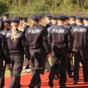 Mehrere Polizisten und Polizistinnen in Uniform gehen nebeneinander über einen Sportplatz