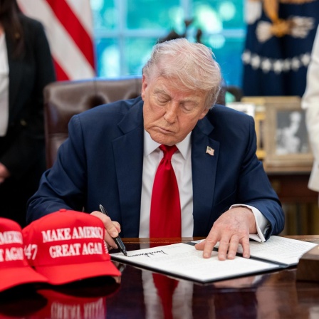 Donald Trump unterzeichnet ein Dekret an seinem Schreibtisch im Oval Office.