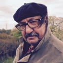 Der Autor und Liedermacher Manfred Maurenbrecher trägt Brille und Mütze und steht in der Natur. Der Wind bläst ihm die Haare ins Gesicht.
