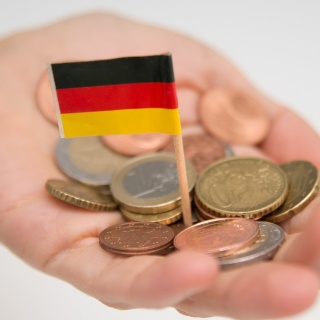 Eine Frau hält Geldstuecke in der Hand, zwischen denen eine kleine Deutschlandfahne steckt.