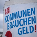 &#034;SOS. Kommunen brauchen Geld&#034;, steht auf einem Banner, das an einer Hauswand in Berlin hängt.