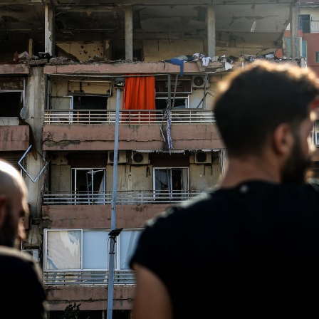 Personen schauen auf ein beschädigtes Wohnhaus, das in der Nacht von einem israelischen Luftangriff in Beirut getroffen wurde.