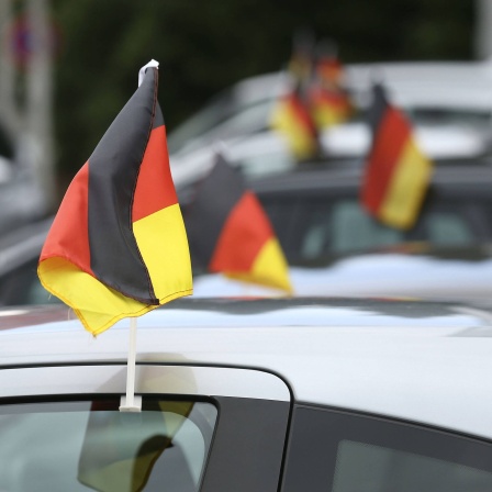 Deutschlandfähnchen an einem Auto:  Wenn jedes Auto mit zwei Fähnchen im Schnitt während eines Fußballturniers 100 Kilometer zurücklegt, bedeutet dies bundesweit einen Mehrverbrauch von rund 3 Millionen Litern.