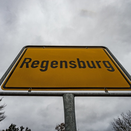 ARCHIV - 22.02.2017, Bayern, Regensburg: Dunkle Wolken ziehen über dem Ortsschild von Regensburg (Bayern).  Nirgendwo lebten 2022 so viele Menschen allein wie in der Großstadt in der Oberpfalz, teilte das Unternehmen GfK in Nürnberg am Dienstag mit. Der Anteil der Einpersonenhaushalte lag demnach in der Stadt bei 52,7 Prozent. . (zu dpa: «Regensburg stimmt gegen eine Stadtbahn») Foto: Armin Weigel/dpa +++ dpa-Bildfunk +++ | Bild: dpa-Bildfunk/Armin Weigel