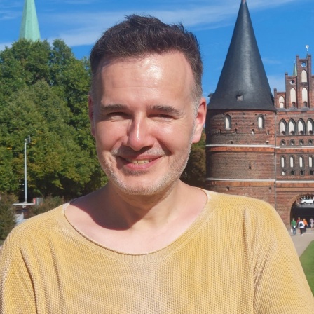 Ein Mann steht vor dem Holstentor in Lübeck. Es ist Christian Martin Lukas, der Tourismus-Chef von Lübeck und Travemünde.