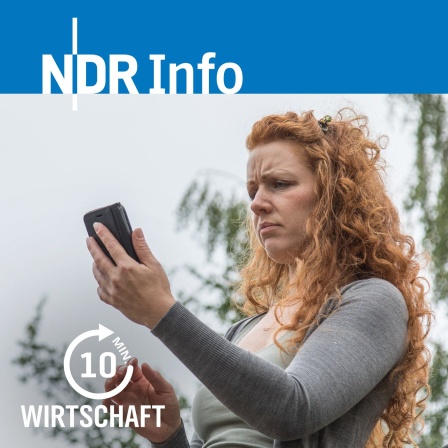 Eine junge Frau steht auf einer Brücke und schaut auf ihr Smartphone.