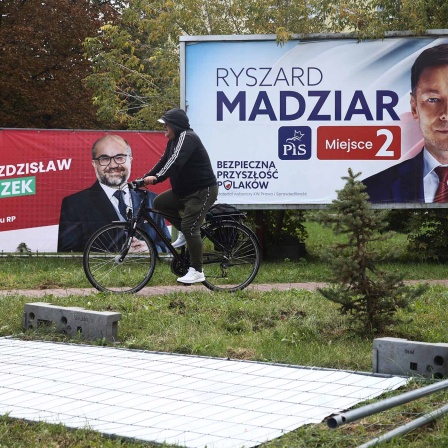 Ein Mann fährt mit dem Fahrrad im polnischen Chelm an Wahlplakaten vorbei. 