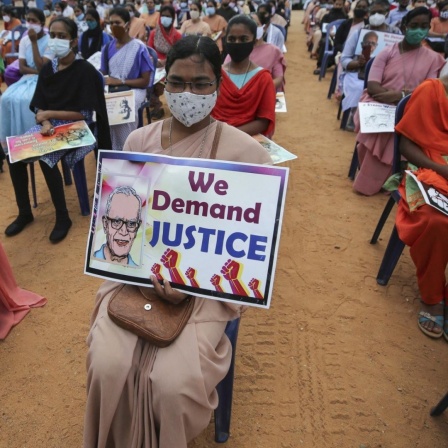 Eine katholische Nonne (Mitte) mit einem Protestplakat fordert die Freilassung des Menschenrechtsaktivisten Stan Swamy bei einer Demonstration in Bengaluru, Indien, am 12. November 2020. Auf dem Plakat ist ein Bild Swamys abgedruckt mit dem Schriftzug "Wi
