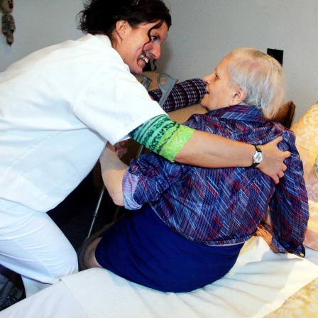 Eine Krankenschwester von der Evangelischen Sozialstation der Diakonie in Freiburg hilft am 27.10.2005 einer bettlägerigen Seniorin aus ihrem Bett.