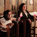 Eine junge Frau und eine alte Frau halten Kerzen in der Hand bei einer Feier der Auferstehung Jesu in einer Kirche in Albanien, 2023.