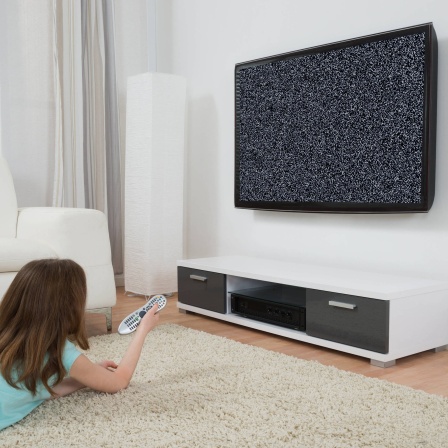 Mädchen mit Fernbedienung vor einem flackernden Fernseher.