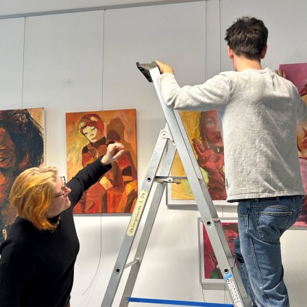 Lehrerin Anne-Katrin Dietrich und Schüler Farin Göbel beim Hängen von Bildern für die Ausstellung "Onirique" im Landeskunstgymnasium Alzey.