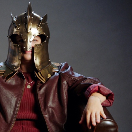 Eine Frau sitzt auf einem Stuhl und trägt eine Maske aus der Serie "Games of Thrones".