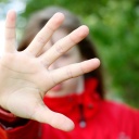 Mädchen hält abwehrend Hand vors Gesicht