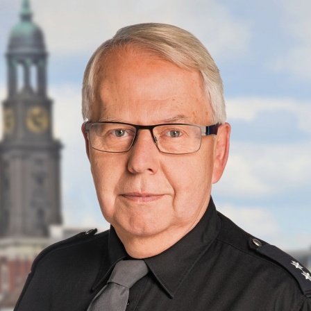 Harald Maack steht in Polizeiuniform vor dem Michel.
