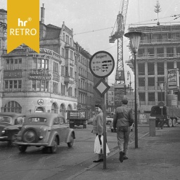 Straßenszene in Frankfurt in der Nachkriegszeit mit Passanten, Lkw und Autos, teils im Bau befindlichem Gebäude und historisches Gebäuden mit Werbeschildern