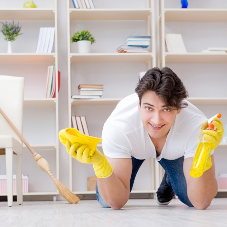 Ein Mann kniet mit Putzhandschuhen auf dem Boden (Bild: IMAGO / agefotostock)