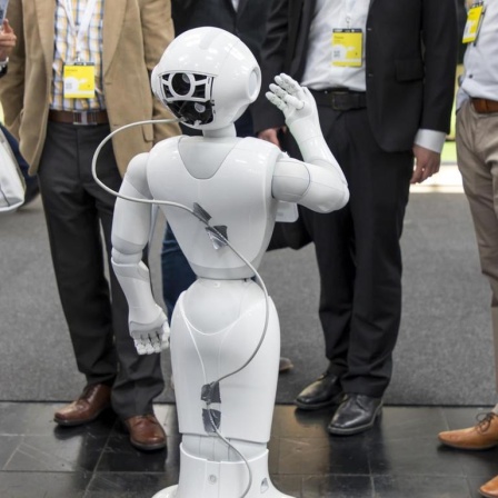 Auf der Messe CEBIT steht ein SoftBank Roboter in einer Gruppe von Menschen.