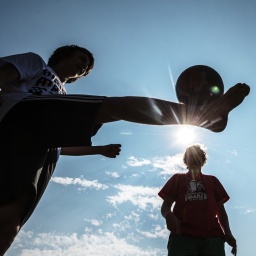 Freizeit-Fußballspieler und Ball im Gegenlicht.