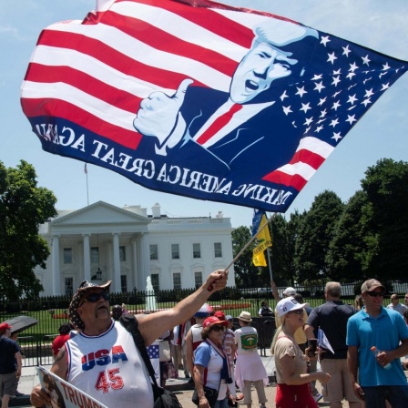 Ein Anhänger von US-Präsident Donald Trump mit einer Flagge vor dem Weißen Haus in Washington, DC.