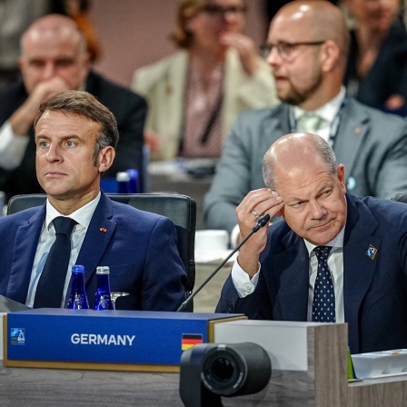 Frankreichs Präsident Emmanuel Macron und Bundeskanzler Olaf Scholz sitzen beim Nato-Gipfel nebeneinander.