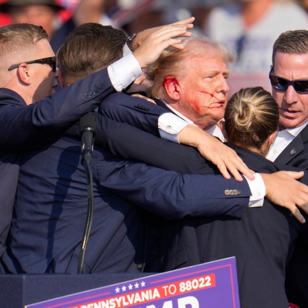 Der republikanische Präsidentschaftsbewerber und frühere US-Präsident Donald Trump wird von Agenten des US-Geheimdienstes Secret Service umringt, als ihm bei einer Wahlkampfveranstaltung von der Bühne geholfen wird.