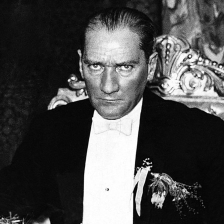 Mustafa Kemel Atatürk sitzt im schwarzen Anzug auf einem Stuhl