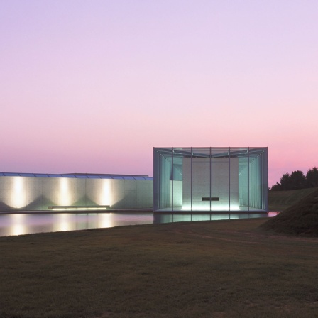 Außenansicht des Ausstellungsgebäude der Langen Foundation in rtölicher Dämmerung.