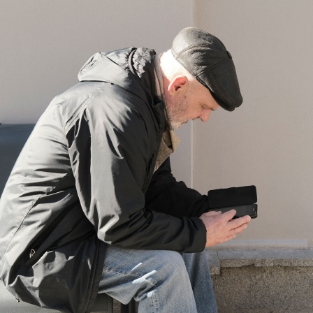 Kyjiw im Krieg: Mann liest Nachrichten am Smartphone © Yevgenia Belorusets