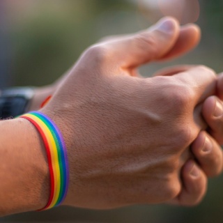 Hände eines jungen Mannes, der ein gay pride-Armband trägt