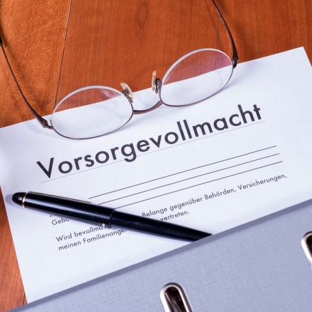 Vorsorgevollmacht, Brille und Stift liegen auf einem Tisch.