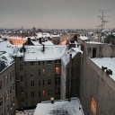 Die Dächer von Berlin im Winter, mit Schnee bedeckt und erleuchteten Fenstern.