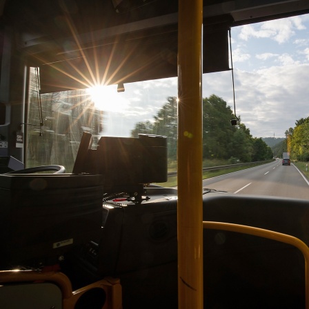 Die Sonne scheint in einen Bus, der auf einer Landstraße fährt
