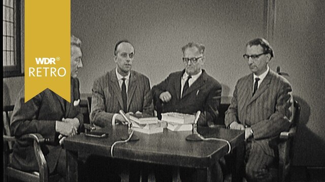 Vier Männer sitzen an einem Tisch und diskutieren über Bücher