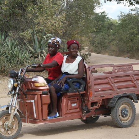In der simbabwischen Stadt Wedza fahren zwei Frauen auf einem Tricycle.