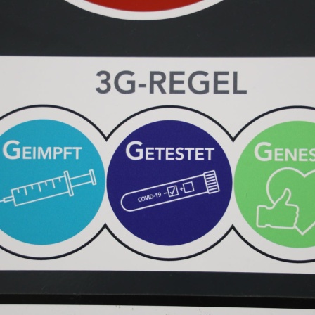 Ein Schild macht deutlich, was Ende 2021 unter 3G-Regeln zu verstehen war: Geimpft wird mit einem Bild von einer Spritze illustriert, Getestet mit dem eines Corona-Tests und Genesen mit einem Daumen-Hoch-Zeichen und einem Herz. 