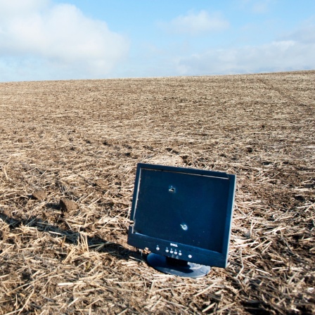 Ein kaputter Computerbildschirm steht auf einem leeren Feld.
