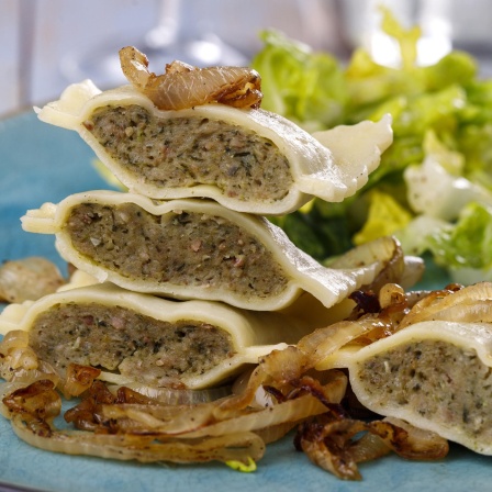 Maultaschen, aufgeschnitten und platziert auf einem blauen Teller.