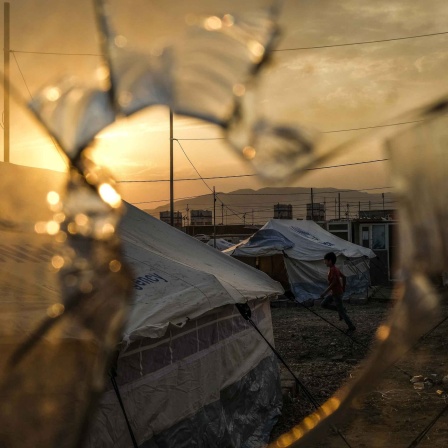 Ein zerschossene Scheibe, dahinter das Flüchtlingscamp Badarash im Nordirak.