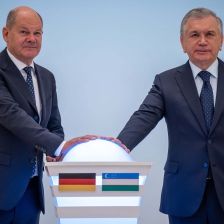 Bundeskanzler Olaf Scholz (SPD, l) drückt nach am Deutsch-Ukrainischen Wirtschaftsforum einen Buzzer neben Schawkat Mirsijojew, Präsident von Usbekistan, zur Eröffnung einer Usbekisch-Deutschen Verwaltungsschule (16.09.2024).