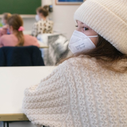 Schülerinnen und Schüler sitzen mit Mund-Nasen-Schutz im Klassenzimmer