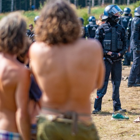 Zahlreiche Polizeibeamte stehen beim "Rainbow Gathering" neben Campern.