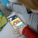 Ein Kleinkind schaut sich Kindervideos auf einem Smartphone an.