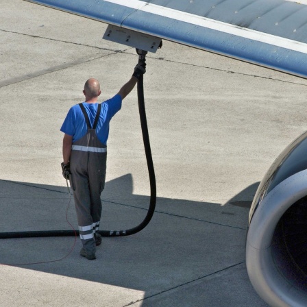 Symbolblig: Ein Mensch betankt ein Flugzeug.