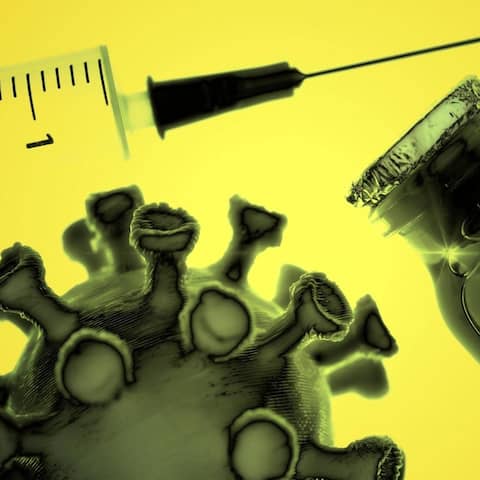Spritze, ein Fläschchen mit Impfstoff und ein Coronavirus-Modell sind vor gelbem Hintergrund zu sehen. 