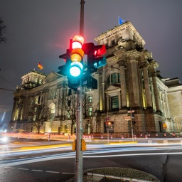 Eine Ampel leuchtet in einer Aufnahme mit Langzeitbelichtung am Morgen vor dem Reichstagsgebäude in allen drei Phasen.