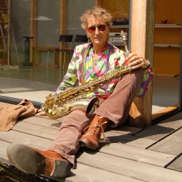 Ein Mann mit Saxophon sitzt auf dem Boden